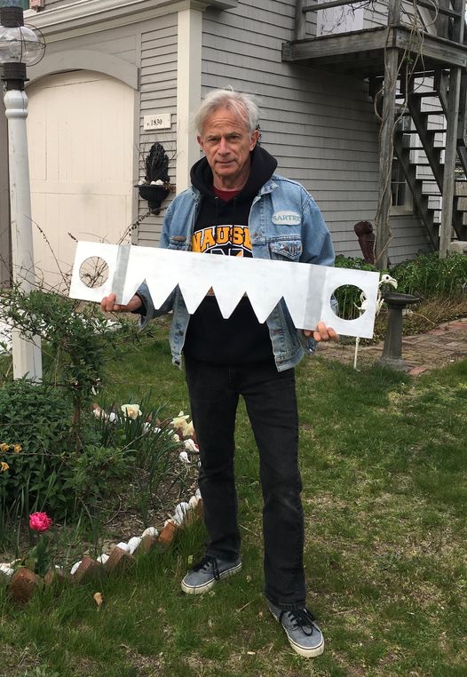 A man holding up a large paper saw.